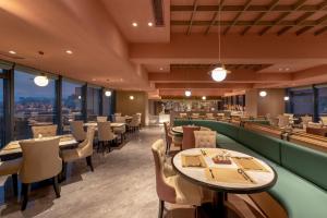 um restaurante com mesas, cadeiras e janelas em Grand New Century Hotel Binjiang Hangzhou em Hangzhou