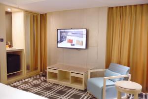 um quarto de hotel com uma televisão e uma cadeira em Olah Poshtel Taichung Wenxin em Taichung