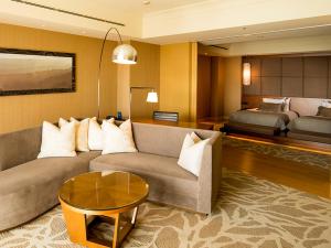 a living room with a couch and a bed at Shima Kanko Hotel The Bay Suites in Shima