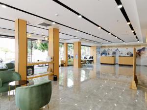 een lobby met groene stoelen, tafels en ramen bij Connar Hotel - Shenzhen Futian in Shenzhen