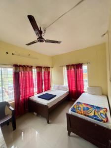 a bedroom with two beds and a ceiling fan at Sree Shanmuga Residency in Vagamon