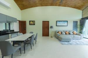 een woonkamer met een bank en een tafel en stoelen bij ขนอม คิริณณ์ Khanom Kirin Private Pool Villa in Ban Plau