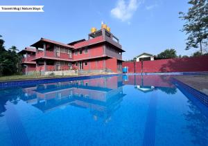 a house with a swimming pool in front of a building at Pepper Corn Retreat by Travent Mug in Sakleshpur