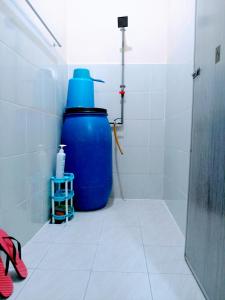 un baño con un gran barril azul en la esquina en ILHAM HOMESTAY Taman Sejati Mile 7, en Sandakan