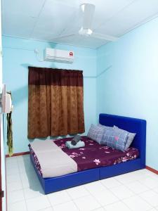 Cette chambre bleue comprend un lit et une fenêtre. dans l'établissement ILHAM HOMESTAY Taman Sejati Mile 7, à Sandakan