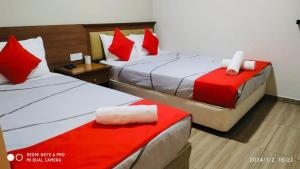 two beds in a hotel room with red pillows at Hotel Casa Reo in Kampong Bagan Lalang