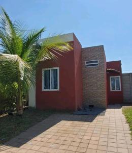 una casa roja con una palmera delante de ella en marhabibi home en Sonsonate