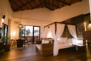 愛妮島的住宿－Nacpan Beach Resort，一间带一张天蓬床的卧室,位于带桌子的房间内