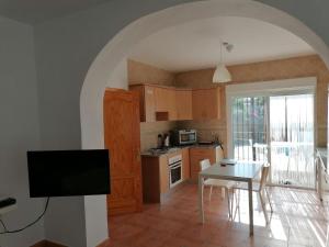 Belvilla by OYO Casa de Aguila في Almogía: مطبخ مع طاولة وتلفزيون في الغرفة