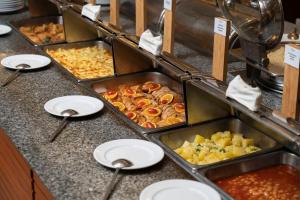 ein Buffet mit Tabletts mit Speisen auf der Theke in der Unterkunft Ravindra Beach Resort & Spa - SHA Extra Plus in Na Jomtien