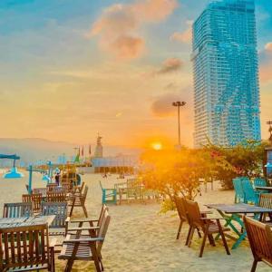 歸仁的住宿－TMS Quy Nhơn View Biển，一个带桌椅的海滩和一座建筑