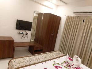 sypialnia z łóżkiem, szafką i telewizorem w obiekcie Chandanvan Club & Resort w mieście Jalālpur