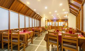 a restaurant with wooden tables and chairs and windows at Treebo Trend Swagatam Inn in Guwahati