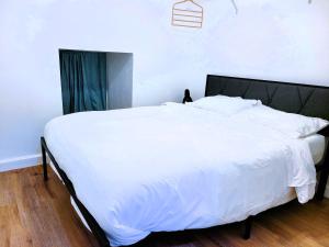 a large white bed in a bedroom with wooden floors at One room in a renovated duplex house near FSU in Tallahassee
