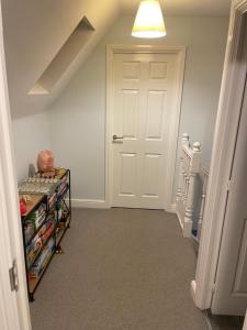 a hallway with a white door and a shelf with books at Beanie’s North Swindon DoubleBed in Blunsdon Saint Andrew