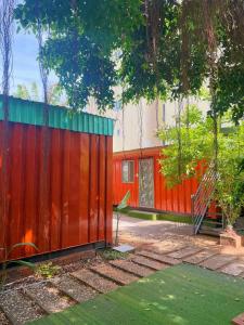 ein roter Zaun neben einem Gebäude mit Bäumen in der Unterkunft Thùng Thép Homestay in Vũng Tàu