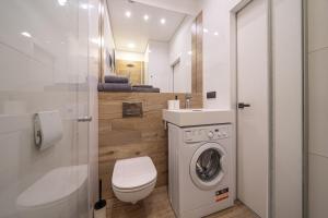 een badkamer met wasmachine en toilet bij Seaside Escape in Dzintaru Studio Apartments 100m from Beach and Near Forest Park in Jūrmala +36 foto's