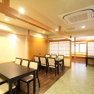 a dining room with tables and chairs and windows at Kamogawakan in Kyoto