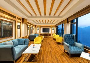 uma sala de estar com sofás azuis e cadeiras amarelas em jüSTa Cliffend Resort & Spa, Mashobra em Kīar