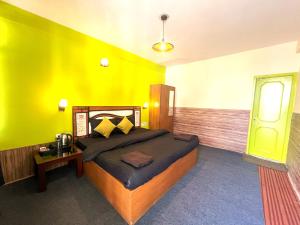 a bedroom with a bed and a yellow wall at Trippy Turtle Hostel in Manāli