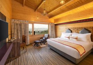 een slaapkamer met een bed, een bureau en een televisie bij jüSTa Cliffend Resort & Spa, Mashobra in Kīar