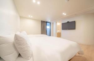a bedroom with a white bed and a flat screen tv at H Moment Hotel Yeonsan in Busan