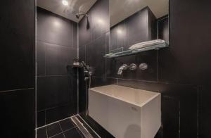 a bathroom with a white sink and black tiles at H Moment Hotel Yeonsan in Busan +21 photos