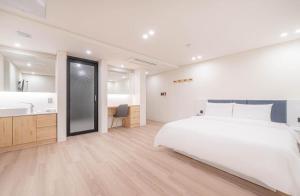 a bedroom with a large white bed and a bathroom at H Moment Hotel Yeonsan in Busan