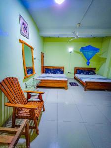 a room with two beds and a chair and a mirror at Dinesh Safari Homestay in Udawalawe