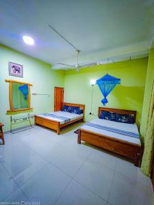 two beds in a room with green walls at Dinesh Safari Homestay in Udawalawe