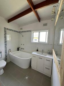 a bathroom with a tub and a toilet and a sink at By the Bay Beach Shack in Vincentia