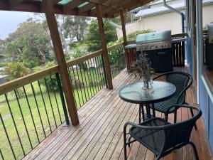a patio with a table and chairs on a deck at By the Bay Beach Shack in Vincentia +2 photos