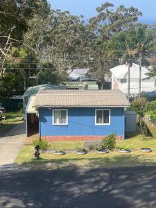 a blue house with a dog in front of it at By the Bay Beach Shack in Vincentia