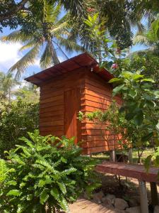 una pequeña casa de madera con un banco en un jardín en Coco Cabins by Thush en Bentota