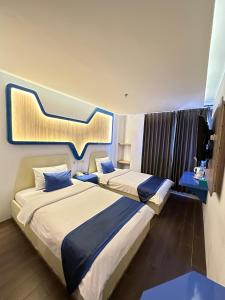 twee bedden in een kamer met een groot instrument aan de muur bij Golden Palace Hotel in Batu Merah