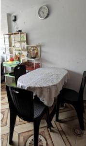LA POSADA GOLDON CHASQUI Lima PERU في ليما: طاولة غرفة طعام مع كرسيين وساعة على الحائط