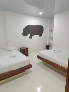 a room with two beds and a bear on the wall at HOTEL EL EMPERADOR in Doradal