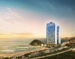 a tall building on a beach next to the ocean at Surf Resort JD Yangyang in Yangyang