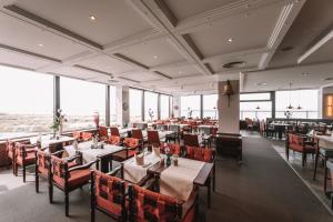 a dining room with tables and chairs and windows at Hotel Neptun in Warnemünde