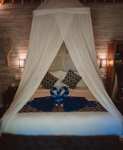 a bed with a canopy with a blue bow at The Lucky Cottage in Nusa Lembongan