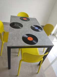 a table with records on it with yellow chairs at Sorriso Flat n.9 - Entire Unit in St. Paul's Bay