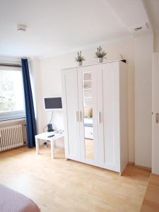 ein weißer Schrank mit Pflanzen darüber in einem Raum in der Unterkunft Apartment am Bach in Augsburg