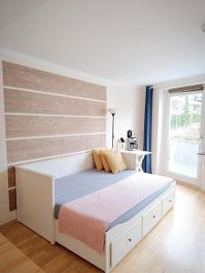 Schlafzimmer mit einem weißen Bett mit einem Kopfteil aus Holz in der Unterkunft Apartment am Bach in Augsburg