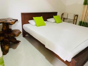 a bedroom with a bed with two green pillows at Fairview Dill homestay in Sigiriya