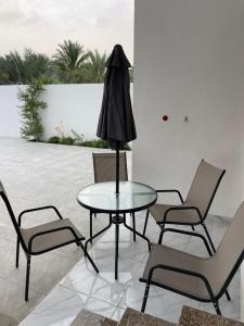een tafel met stoelen en een zwarte paraplu erop bij نزل الغيم -Cloudinn in Qārūt al ‘Ulyā