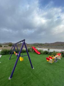 a group of playground equipment on a green field at نزل الغيم -Cloudinn in Qārūt al ‘Ulyā