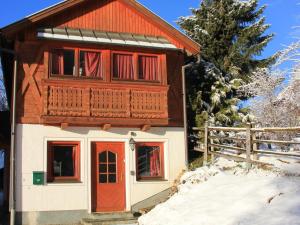 マリアプファルにあるPrivate Holiday Home in Mariapfarr with Lovely Gardenの雪の赤い扉のある小さな家