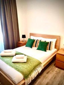 een slaapkamer met een groot bed met groene kussens bij 2 Bedroom serviced apartment in Londen