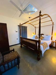 a bedroom with a four poster bed and a chair at Happy Valley Residence Unawatuna in Galle