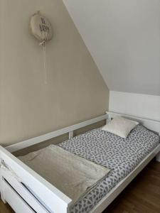 a small bed in a room with a white wall at La maison dAna in Plouézec